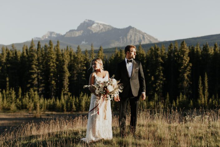 Boho bride standing with bridal bouquet next to groom in the Rocky Mountains
