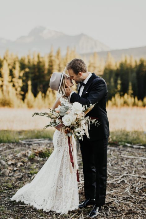 Bride and groom kissing in the Rocky Mountains with a boho bridal bouquet