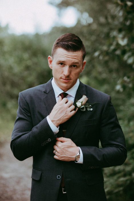 Groom in dark grey suit with mauve rose boutonniere