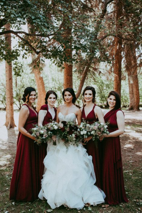 Rikki Lee's burgundy bridal party carrying bouquets designed with dahlias, garden roses, roses, lisianthus, plumosa and eucalyptus