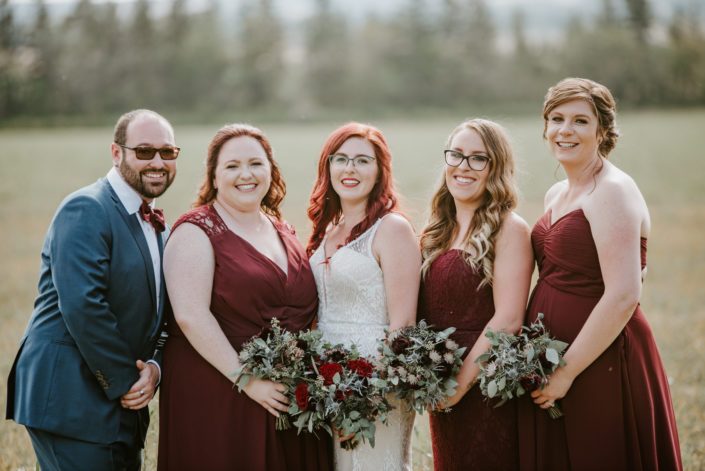 Hailey's burgundy and royal blue bridesmaids and bridesman with bouquets designed with burgundy astrantia, chocolate cosmos, eryngium, burgundy ranunculus, black bacarra roses, blue viburnum berries and eucalyptus