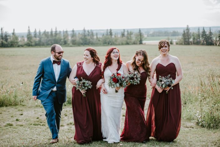 Bride, bridesmaids and bridesman walking with burgundy bouquets