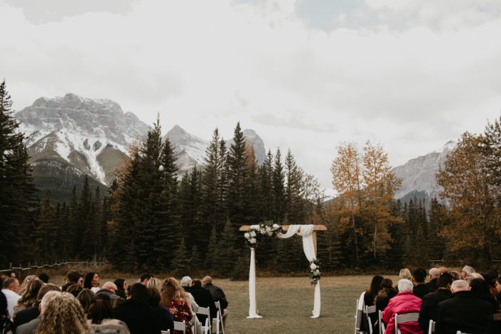 Canmore outdoor ceremony archway draped with white linens with white hydrangea flower arrangements