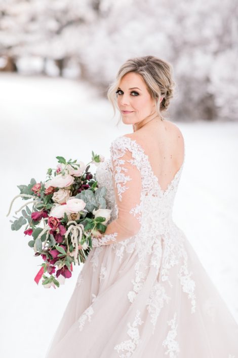 Bride walking in a winter wonderland with blush and burgundy bouquet