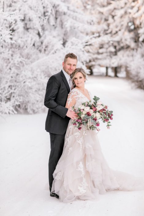Bride and groom with blush and burgundy bouquet in the snowy winter