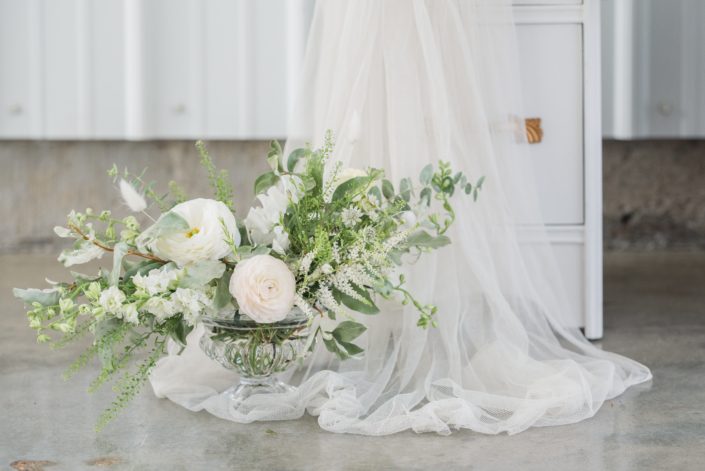 White and green romantic floral arrangement designed with poppies, astilbe, sweet peas, snapdragons, bunny tails and a mixed variety of greenery.