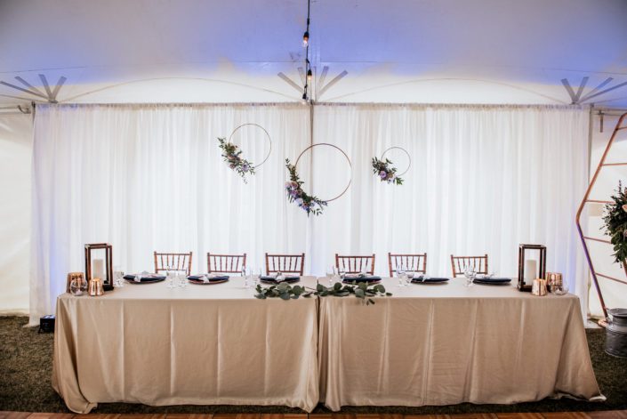 Erin and Nick's Mauve and Navy Winter Wedding Head Table decorated with copper hoops with floral accents