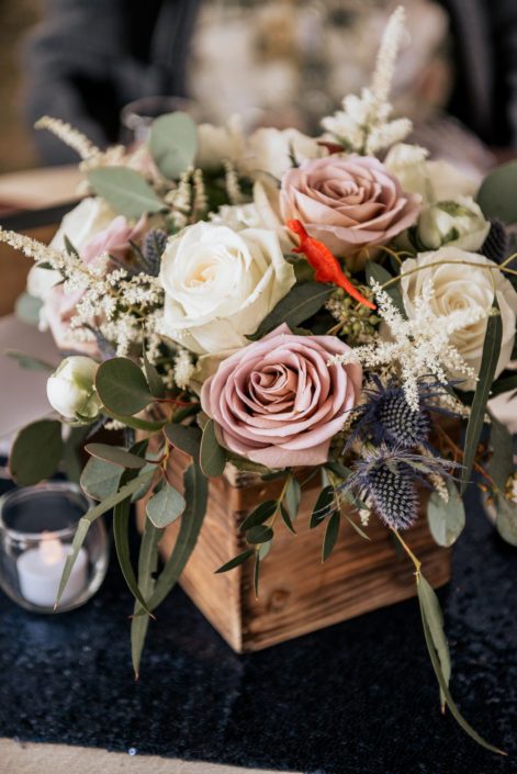 Mauve, ivory and navy flowers such as amnesia roses, playa blanca roses, white o'hara garden roses, astilbe and eryngium in a wooden box