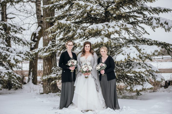 Mauve and Navy winter wedding; bride and bridesmaids wearing black, grey and white and carrying mauve and ivory bouquets accented by navy