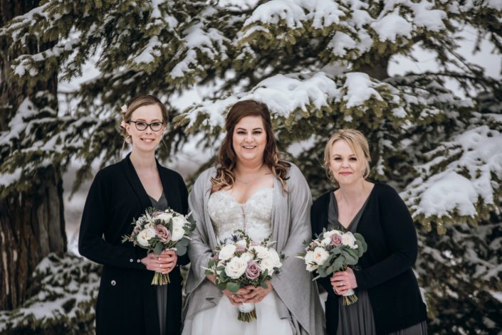 Bride and bridesmaids carrying mauve and ivory bouquets designed with astilbe, eryngium, white o'hara garden roses, ranunculus, amnesia roses, playa blanca roses, and eucalyptus