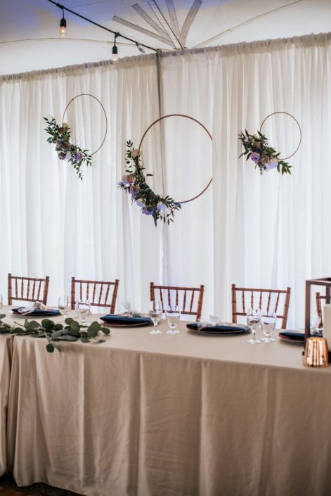 Erin and Nick's Mauve and Navy Winter Wedding head table decorated with copper hoops accented by flowers