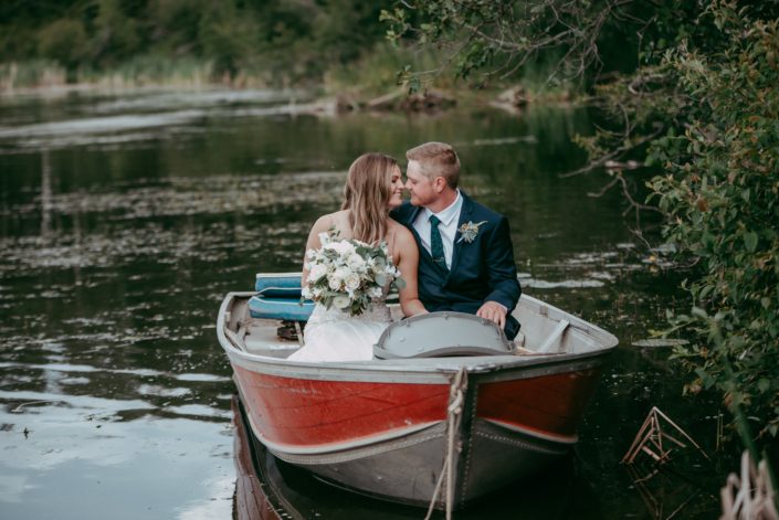 Kylie and Adam in a boat with white bridal bouquet and boutonniere.