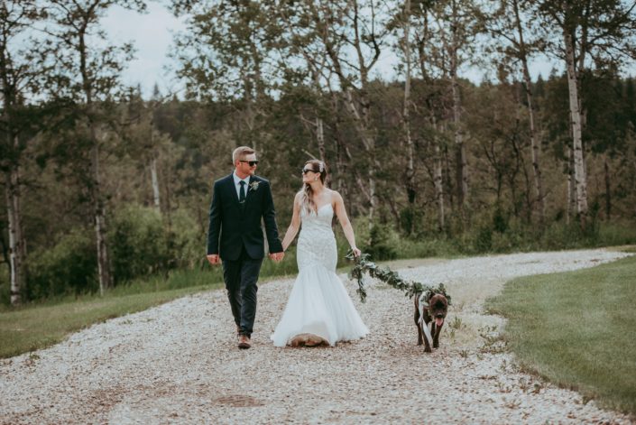 Bride and groom walking dog with eucalyptus garland collar and leash