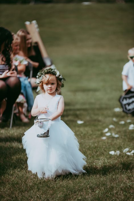 Flower girl wearing white and green flower crown and dropping flower petals