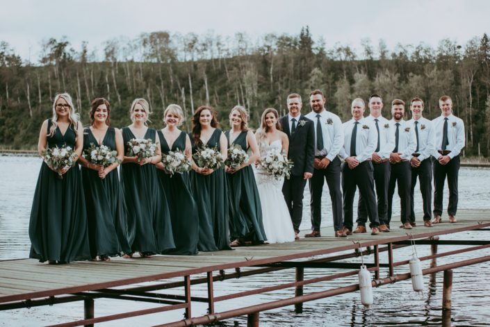 Natural White and Green wedding bridal party; bridesmaids wearing green gowns and holding white and green bouquets; groom and groomsmen wearing boutonnieres