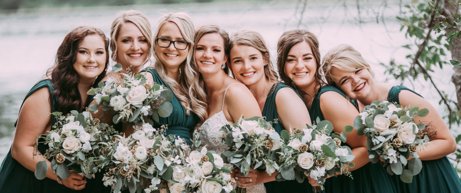 Natural white and green wedding; Bride and bridesmaids wearing green dresses and holding white bouquets featuring roses, ranunculus, astilbe, sweet peas and eucalyptus