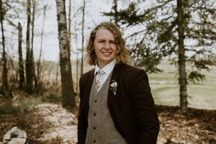 Groom wearing vintage rustic styled suit with a boutonniere designed with astilbe, astrantia and white spray roses