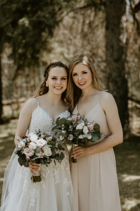 Bride with bridesmaid holding bouquets designed with blush, white and burgundy flowers