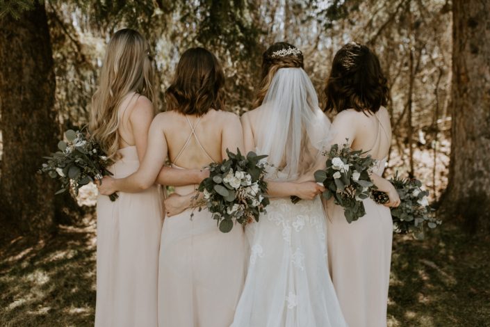 Bride and bridesmaids with blush, white & burgundy bouquets behind their backs