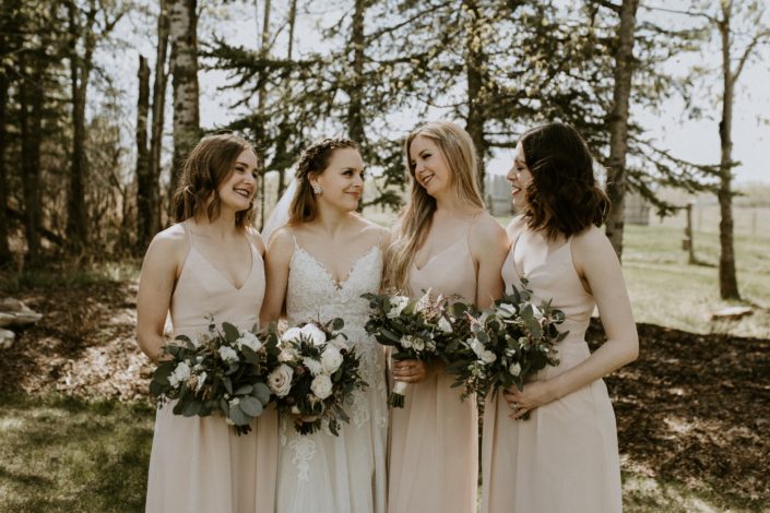 Bride and bridesmaids with bouquets designed with pink astilbe, burgundy astrantia, eryngium, white ranunculus, playa blanca roses and quicksand roses with eucalyptus greenery