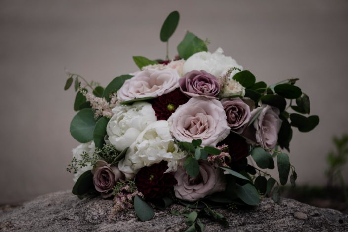 Burgundy and mauve bridal bouquet designed with amnesia and quicksand roses, ranunculus, peonies, dahlias and astilbe with eucalyptus greenery