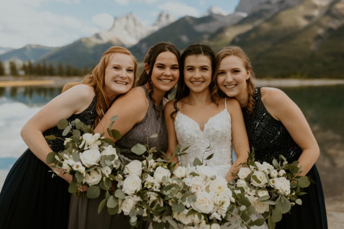 White rural elegance wedding - Bride and bridesmaids with white bouquets featuring lisianthus, ranunculus, roses, spray roses, sweet peas, eucalyptus and Italian Ruscus