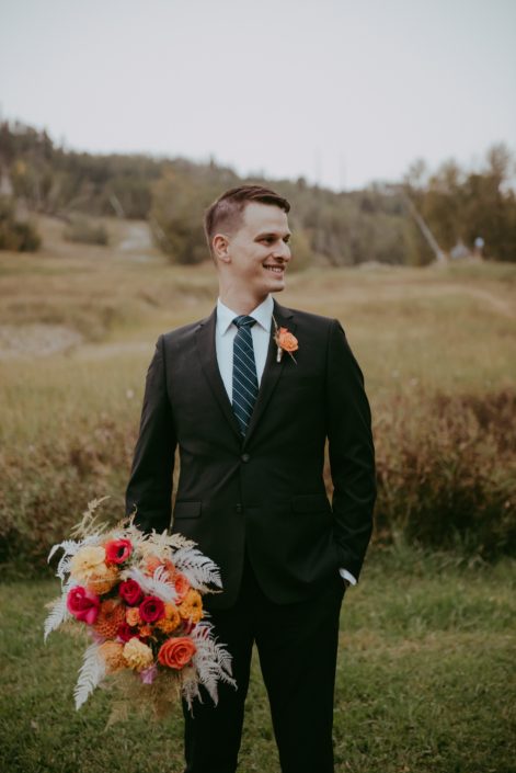 Groom with colourful fuchsia and orange bridal bouquet and boutonniere
