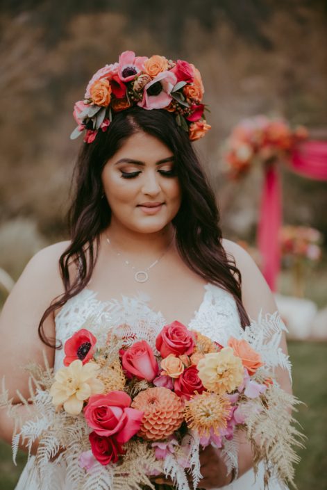 Bride with bold and colourful flower crown and bridal bouquet designed with anemones, zinnias, roses, dahlias, sweet peas, bleached bracken fern, gold plumosa and eucalyptus