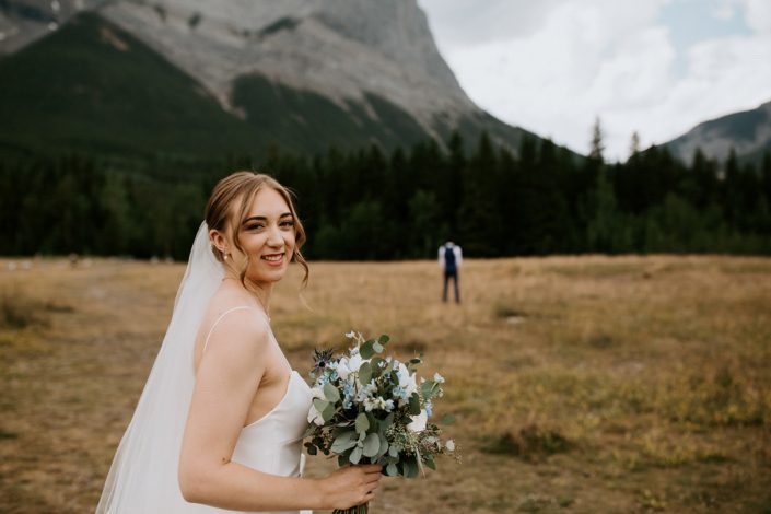 Bride with white and blue bouquet first look in Rocky Mountains near Canmore