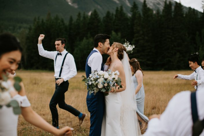 Bride and groom kissing in Rocky Mountains with white and blue bridal bouquet