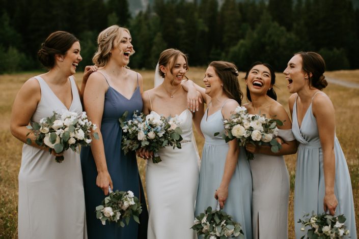 White and Blue Canmore Wedding - Bride with bridesmaids; white and blue dresses; white and blue bouquets featuring roses, ranunculus, sweet peas, forget me nots, eryngium, delphinium and eucalyptus