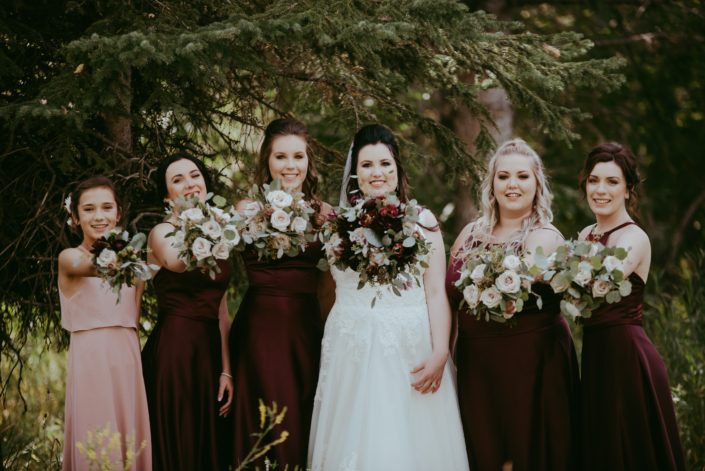 Bride with her bridesmaids and flower girl with burgundy and dusty rose bouquets