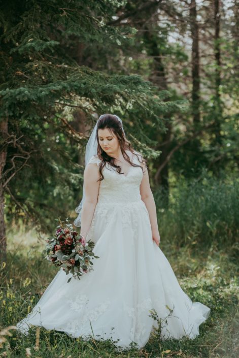 bride with rustic burgundy and dusty rose bouquet in a forest