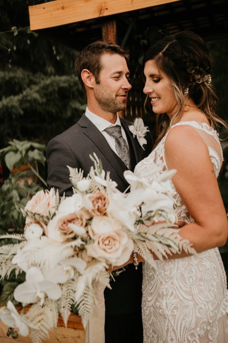Bride and groom with blush and white rustic boho bridal bouquet featuring roses, ranunculus, orchids, bunny tail, bleached bracken fern and olive branches