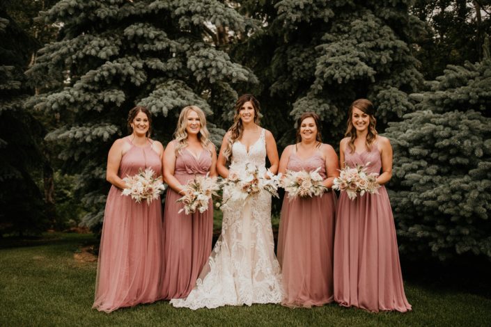 Bride with bridesmaids; rustic boho bouquets designed in white and blush tones including roses, ranunculus, phalenopsis orchids, olive branches, eucalyptus, bunny tail, bleached bracken fern and astilbe; dusty mauve bridesmaids dresses