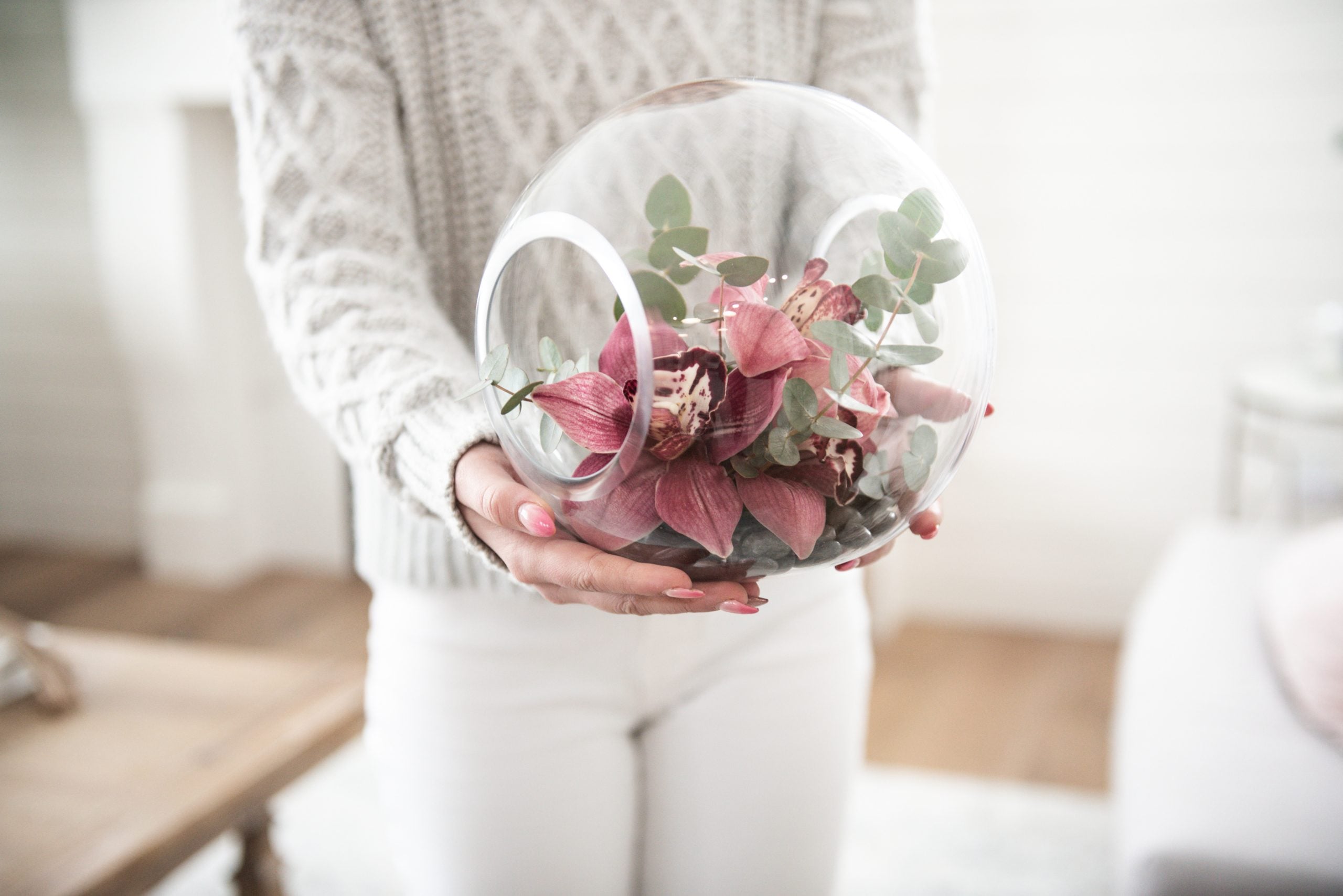 Calyx Emma arrangement featuring orchids and eucalyptus greenery in a glass globe terrarium