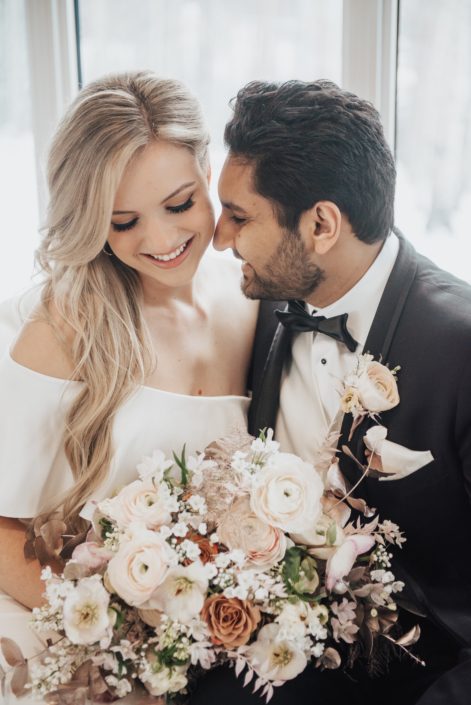 Planning Your Wedding Flowers with Calyx Floral Design: Everything You Need to Know; bride and groom with blush pink, white and rose gold bridal bouquet and boutonniere; roses, ranunculus, hellebores, plumosa, iltalian ruscus, plumosa