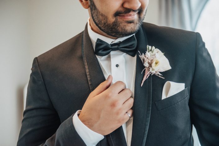Blush boutonniere and black tuxedo with bow tie