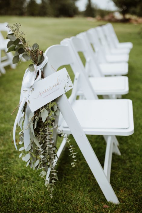 Rusty rose wedding at Hilltop white chairs with aisle markers made of clusters of fresh eucalyptus greenery tied with white ribbons