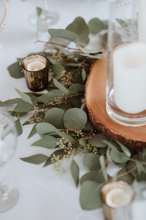 Fresh eucalyptus greenery centrepiece; silver dollar and seeded eucalyptus at the base of tree cookies with candles
