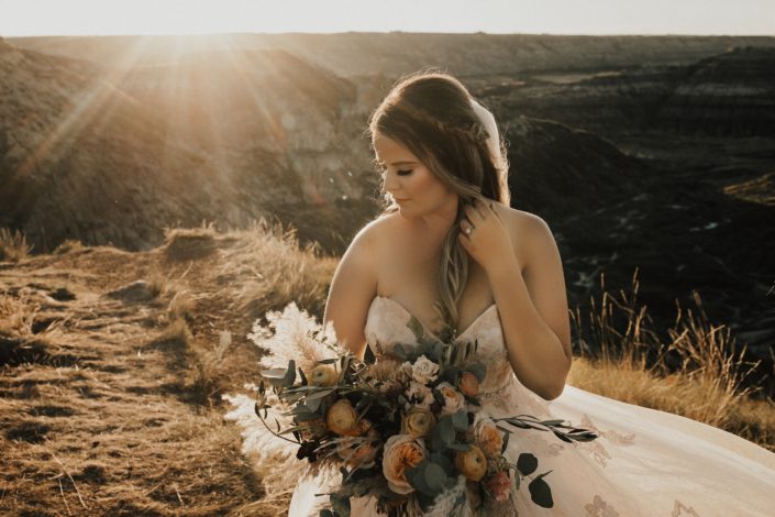Boho Bride with peach and burgundy bridal bouquet at sunset in Drumheller desert