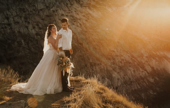 Bride and groom with boho bouquet at sunset
