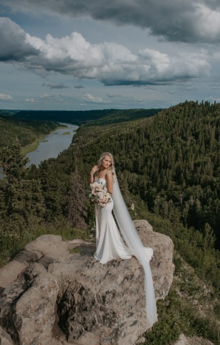Bride standing with bouquet overlooking valley
