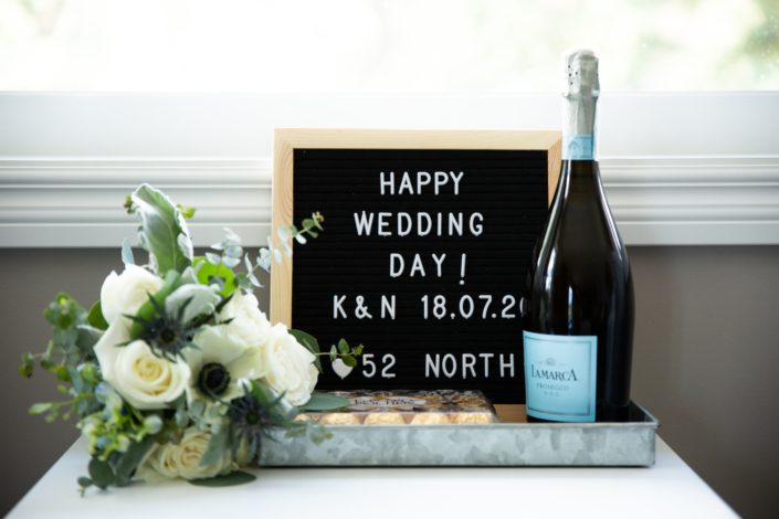Throw bouquet beside wedding sign and champagne