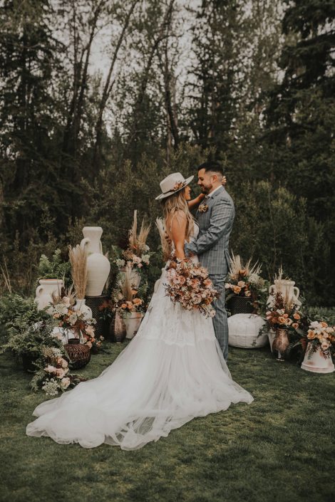Modern Boho Bride and Groom amongst boho flowers, greenery and decor with terracotta toned bridal bouquet