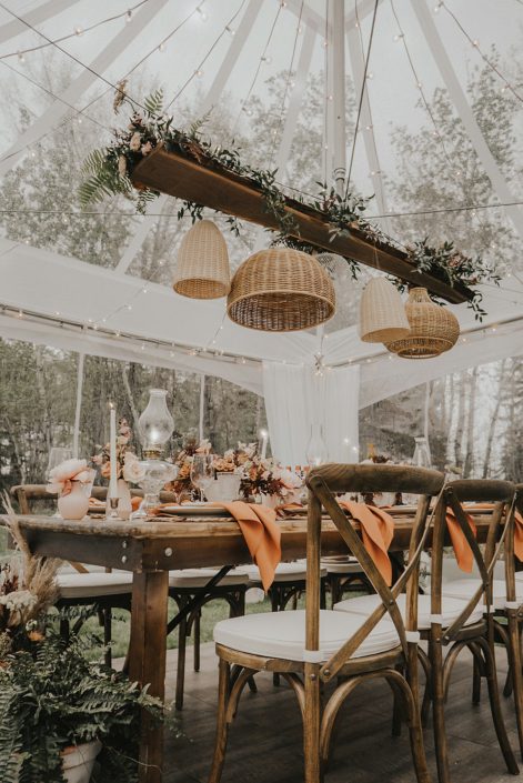 Modern boho tablescape decorated with natural elements and terracotta tones such as woven baskets, greenery, ceramics, pottery and wood with flowers