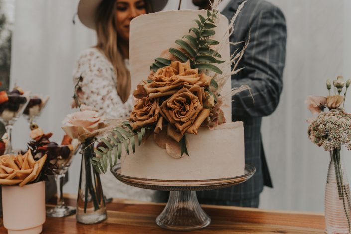 Modern boho and terracotta styled shoot cake decorated with fern, grasses and toffee roses