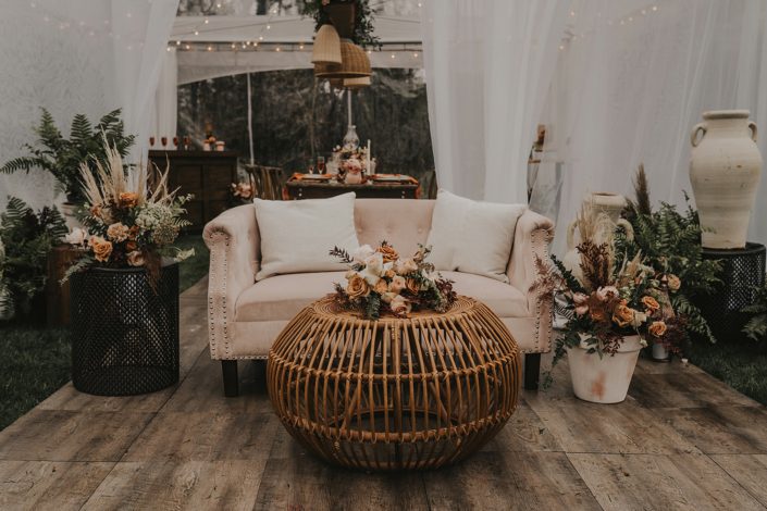 Modern boho seating area with rattan elements and terracotta toned floral arrangements with terracotta pottery and ceramics