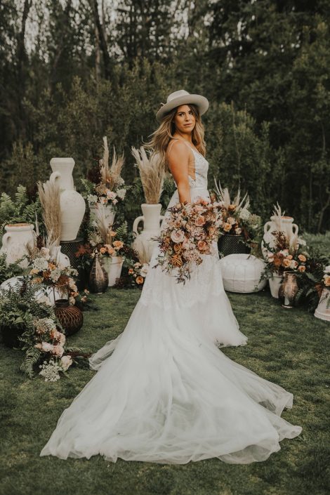 Modern Boho Bride with terracotta toned bouquet surrounded by boho decor and botanicals