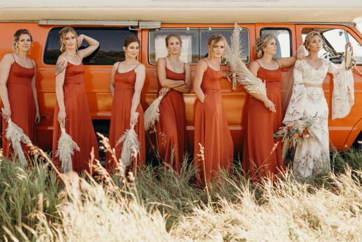 Bridesmaids wearing orange dresses with pampas grass bouquets and boho bride